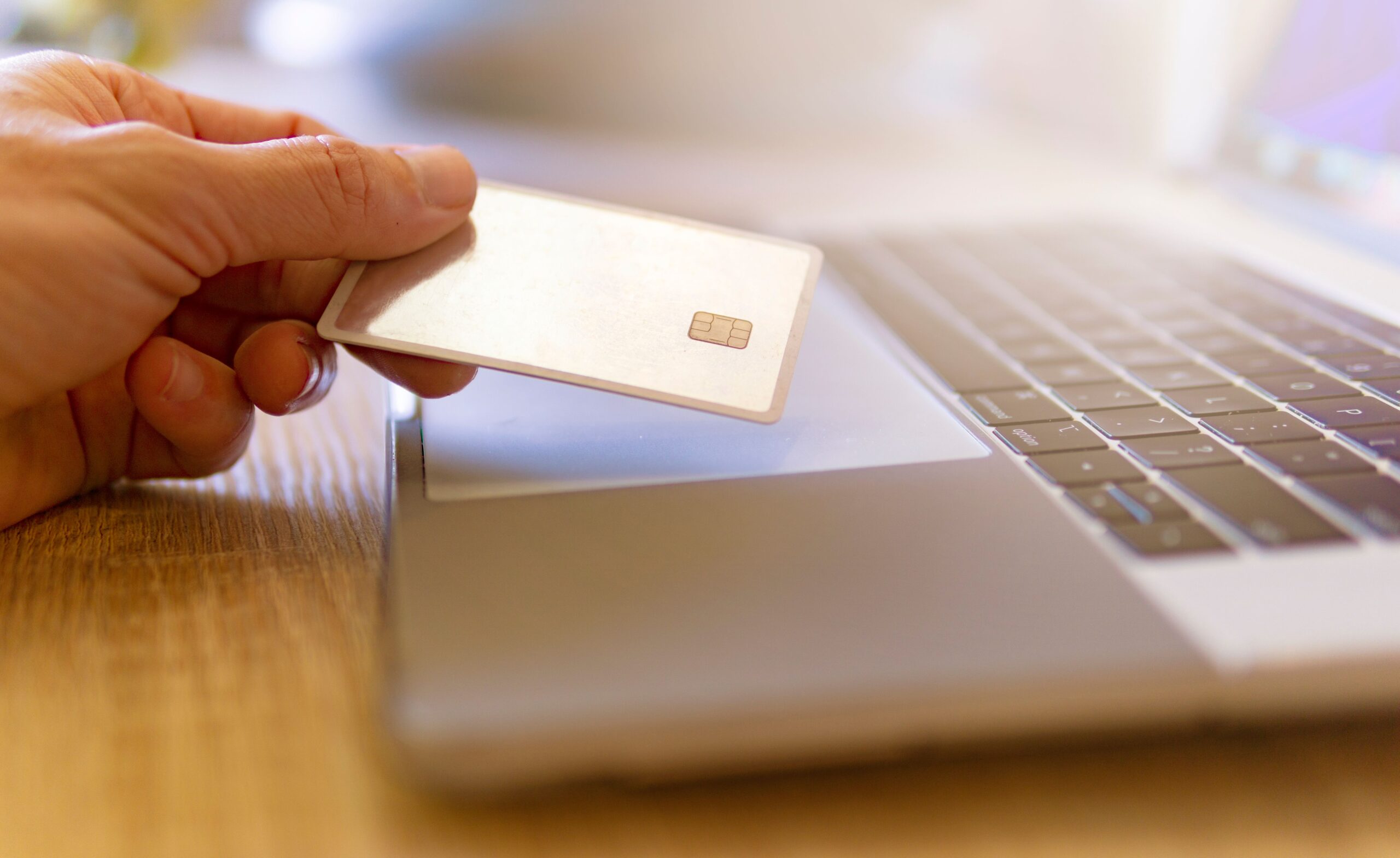 ノートパソコンの前でクレジットカードを持つ手元