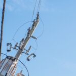 青空を背景に複数のワイヤーが張られた電柱
