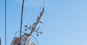 青空を背景に複数のワイヤーが張られた電柱