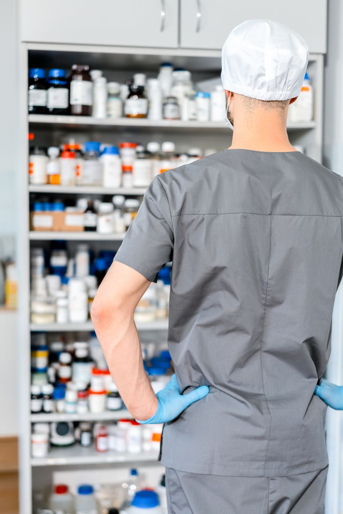 商品棚を整理する薬剤師。区分ごとに並ぶ売り場のイメージ