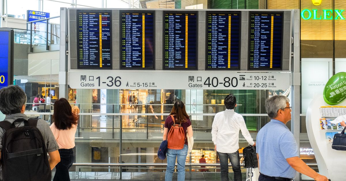 空港の出発案内板を見る人たち