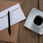 木のテーブルに置かれた封筒と書類とコーヒー