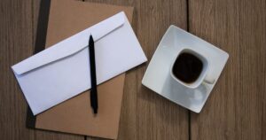 木のテーブルに置かれた封筒と書類とコーヒー