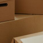 木の床に積まれた段ボール箱。実家の片付けで出る不用品のイメージ