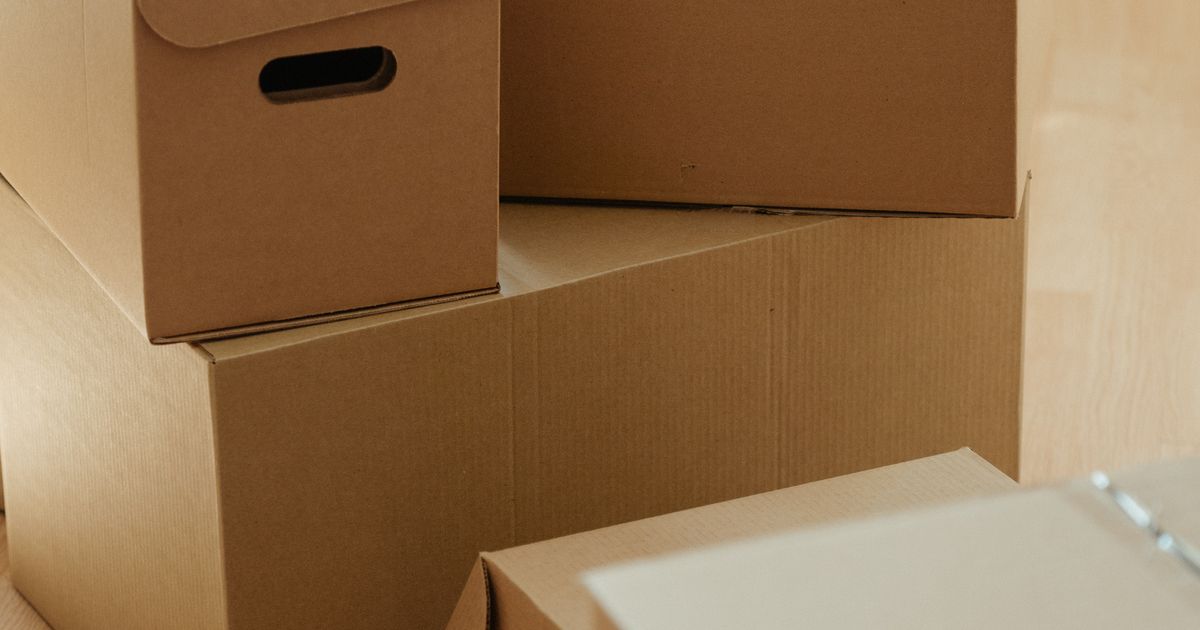 木の床に積まれた段ボール箱。実家の片付けで出る不用品のイメージ
