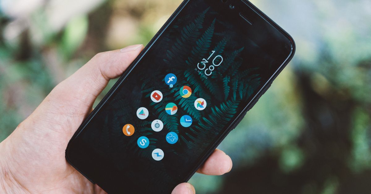 アプリのアイコンが表示されたスマートフォンを手に持っている