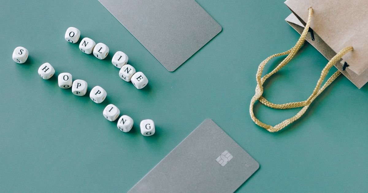 緑の背景に置かれたカードとスマートフォン、買い物袋