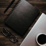 木製デスクに置かれたノートパソコンとコーヒー