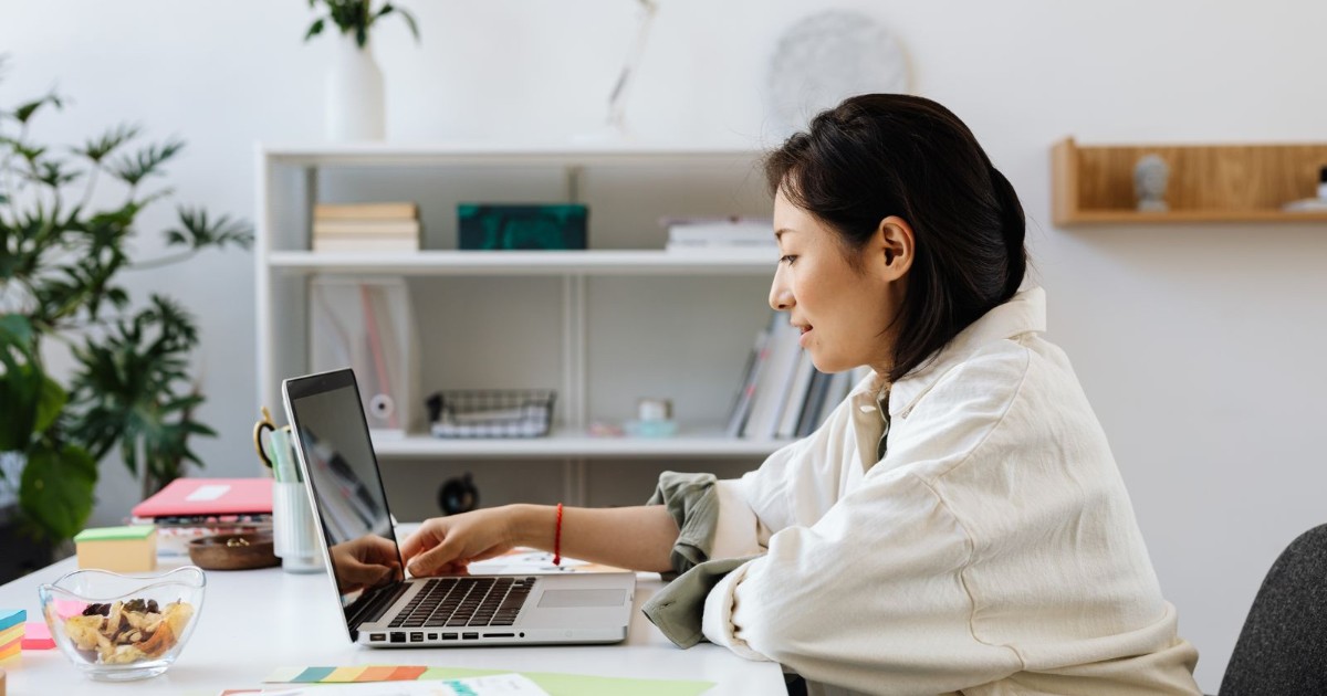 明るい部屋のデスクでノートPCに向かう女性の実写。famifiのイメージ