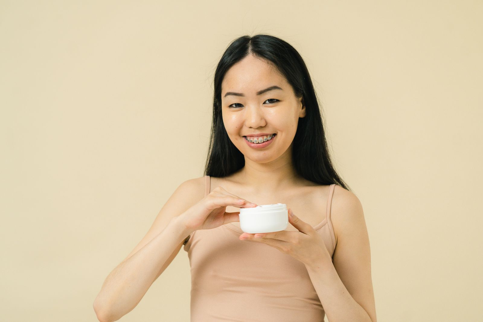 化粧水をなじませる前にオールインワンを手に取る女性
